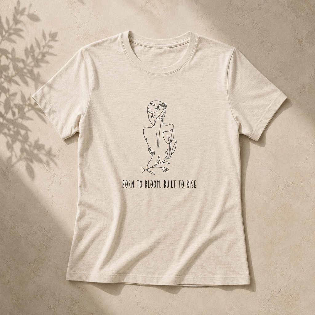 A light beige heather t-shirt with a minimalist black line art illustration of a woman and the text 'BORN TO BLOOM. BUILT TO RISE.