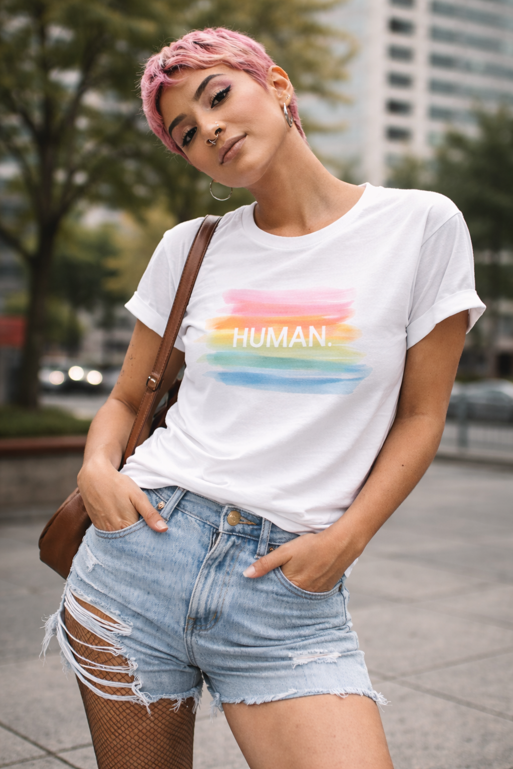 Person wearing a white t-shirt with a rainbow-colored 'HUMAN' graphic in an urban setting.