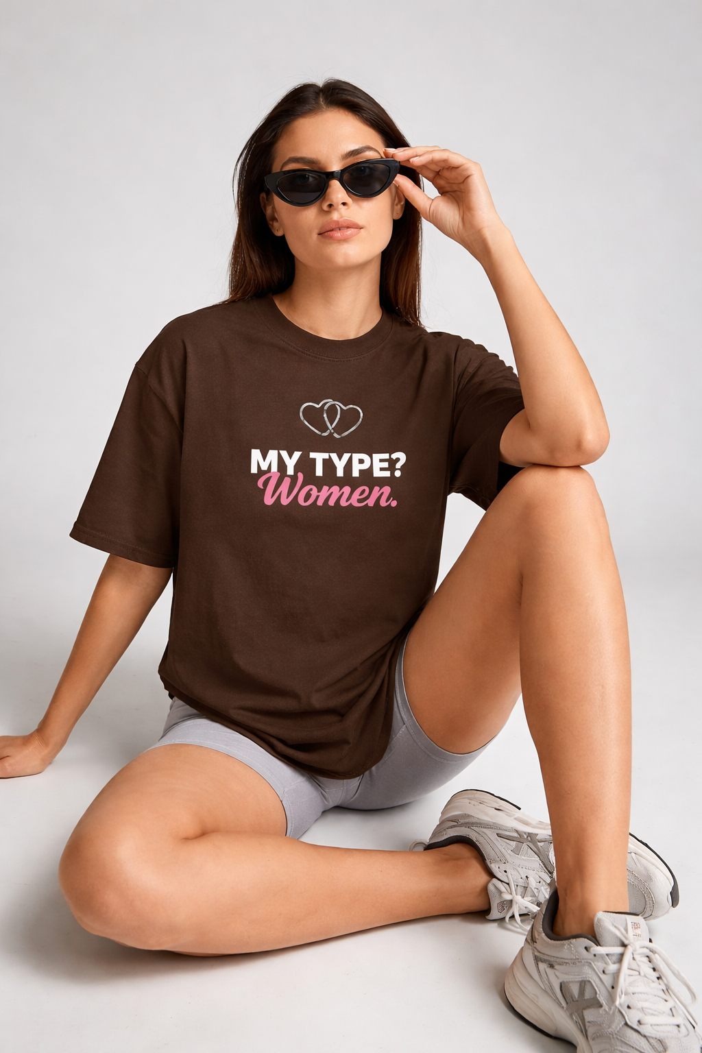 Woman wearing a brown t-shirt with text, sitting on a light gray background