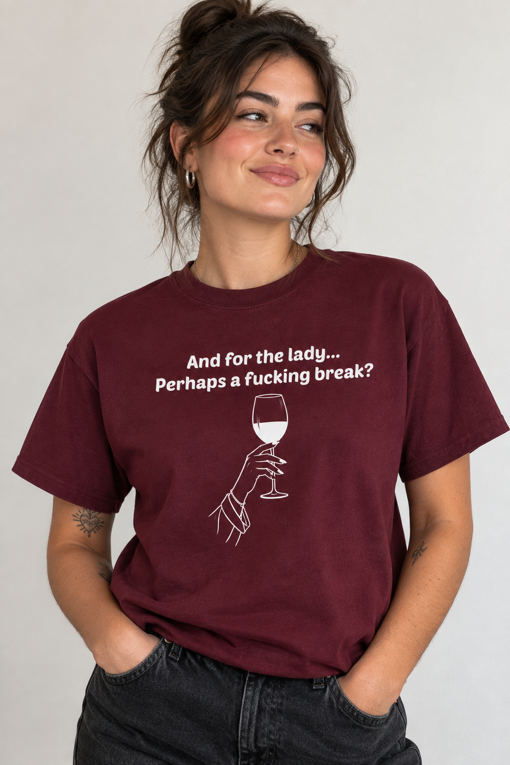 A woman wearing a maroon crewneck t-shirt with a white graphic print that reads 'And for the lady.