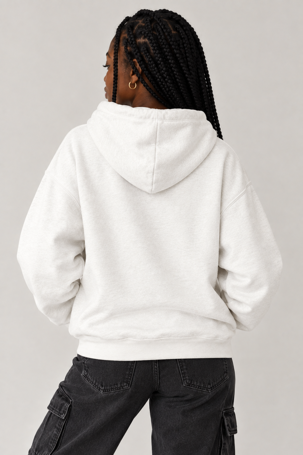A person shown from the back wearing an oversized white hoodie and dark gray cargo pants against a plain light gray studio background.