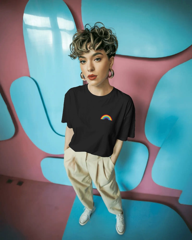 Person wearing a black t-shirt with a rainbow design in a colorful room.