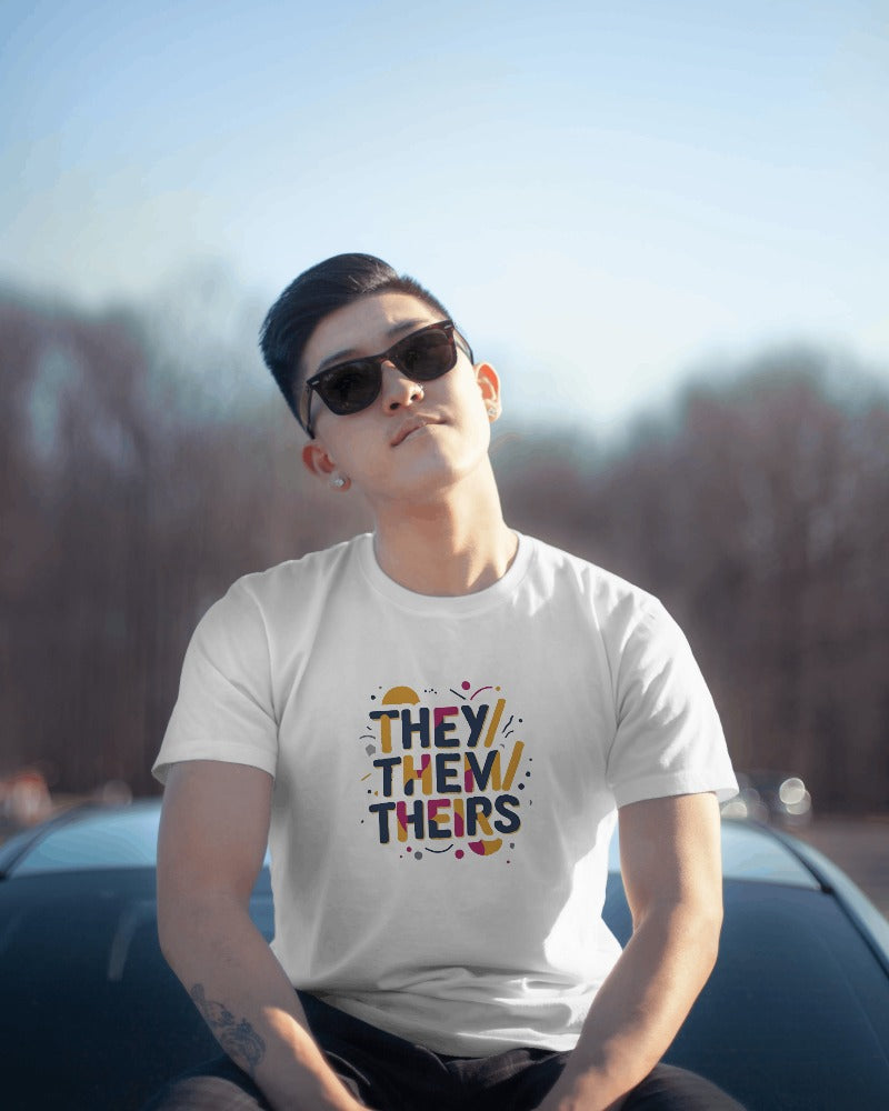 Person wearing a white t-shirt with pronoun text outdoors