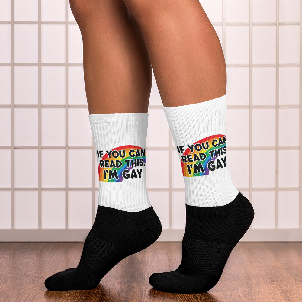 White socks with rainbow text worn by a person on a tiled floor.