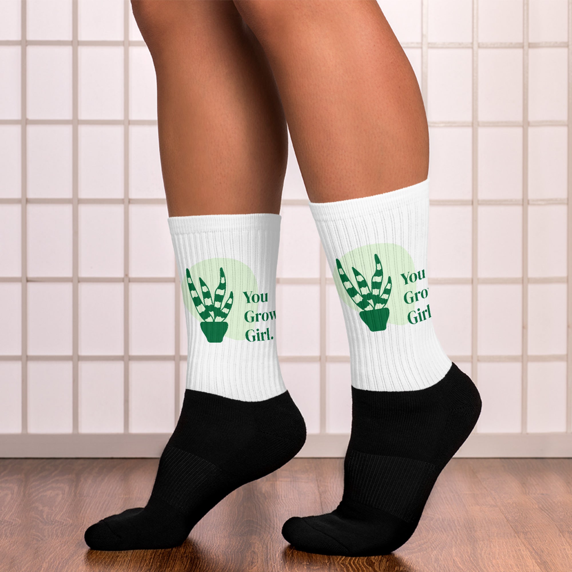 White socks with green text and black socks worn indoors on a tiled floor.
