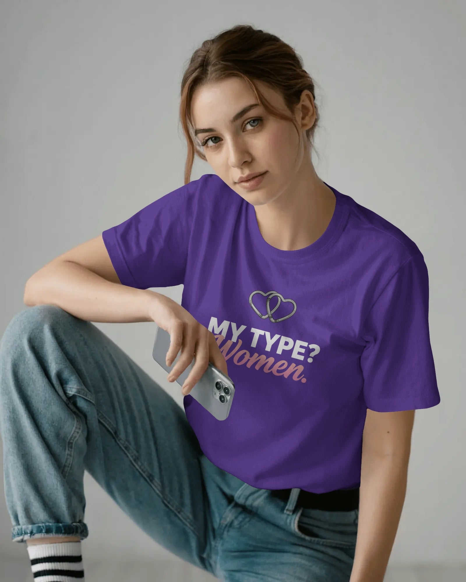 Person wearing a purple t-shirt with text and design, sitting on a gray background
