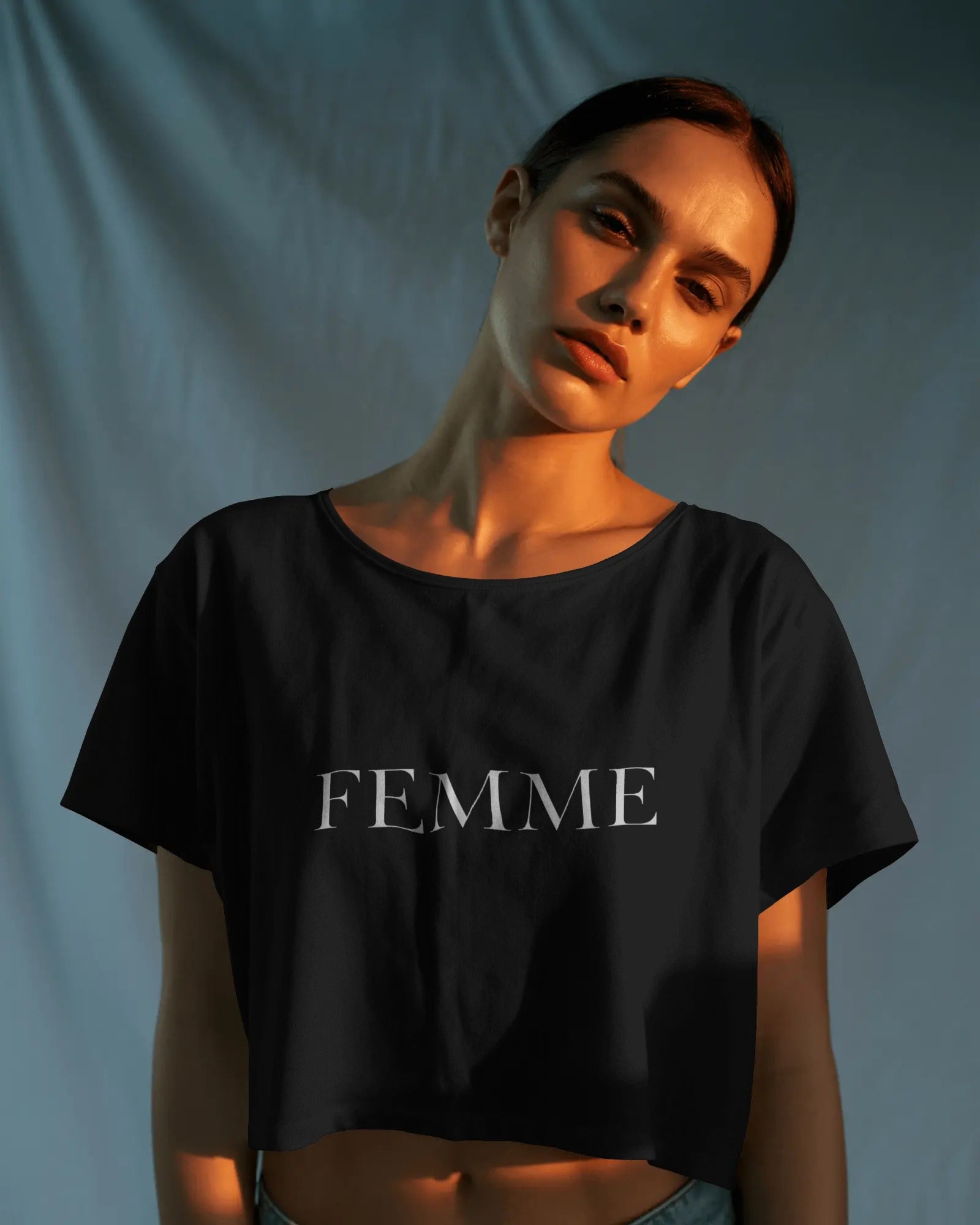 Queer femme model wearing a white FEMME crop top, minimal bold typography