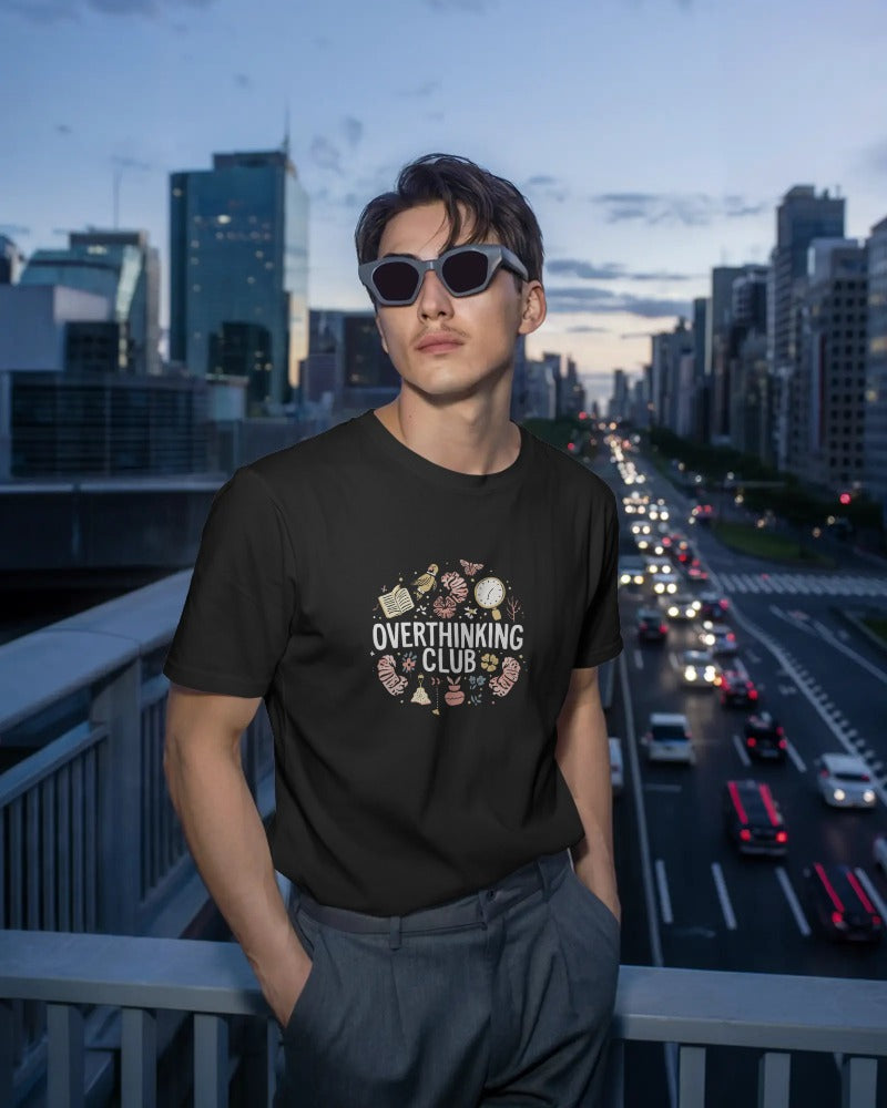 Person wearing a black t-shirt with 'Overthinking Club' design in an urban setting