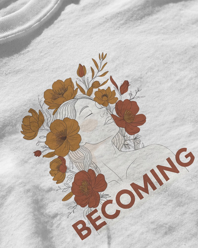 White t-shirt with a floral design and 'BECOMING' text on a white background