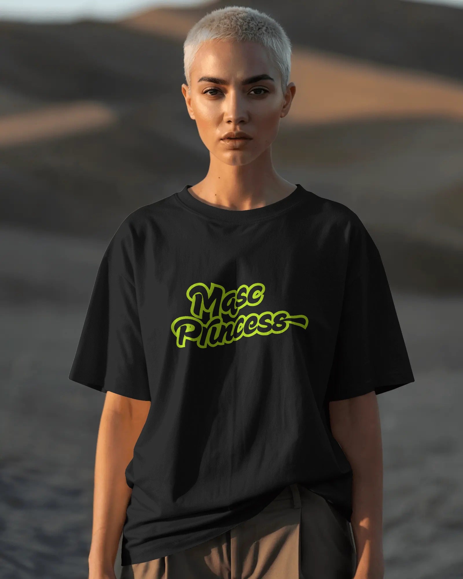 Female model wearing black Masc Princess oversized t-shirt with neon green slogan, styled with ripped jeans and sunglasses, queer streetwear fashion
