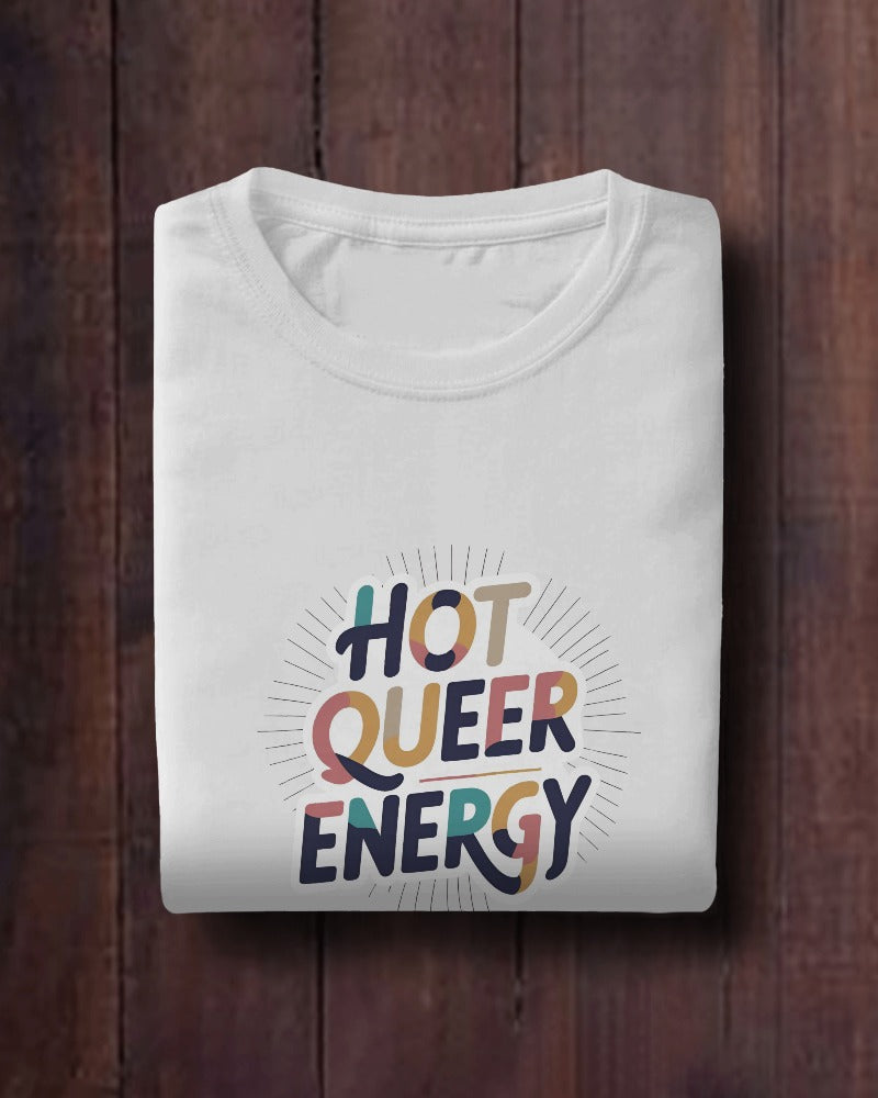 Folded white t-shirt with 'Hot Queer Energy' text on a wooden surface