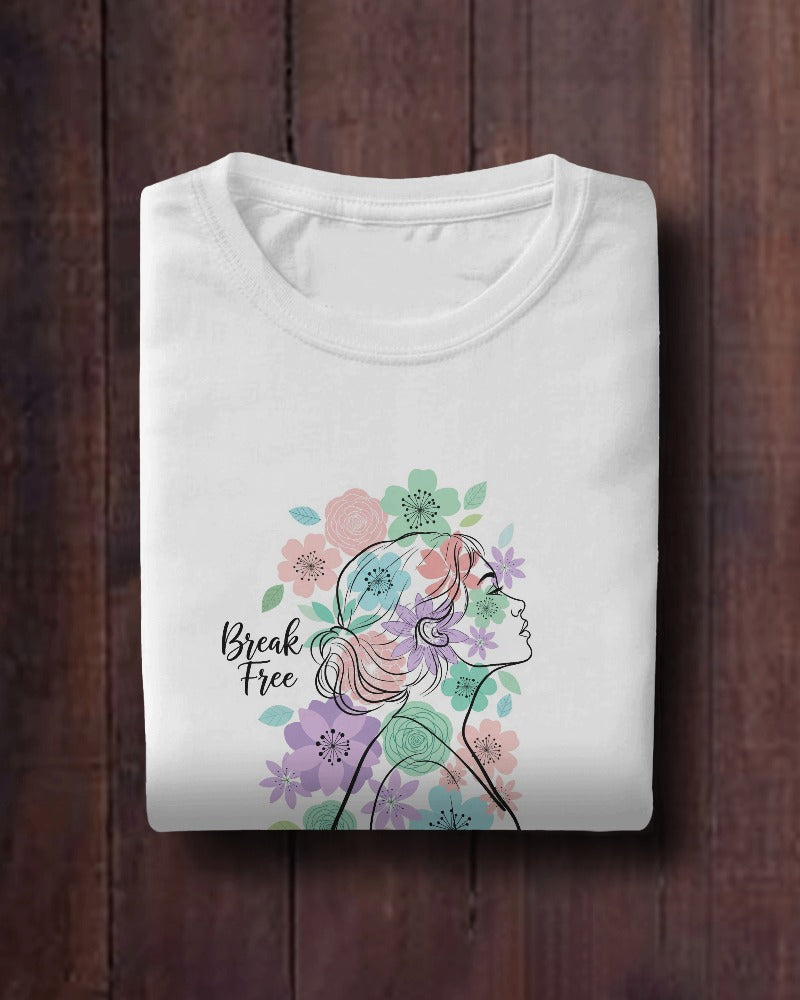 White t-shirt with a colorful design of a woman's profile and flowers on a wooden surface