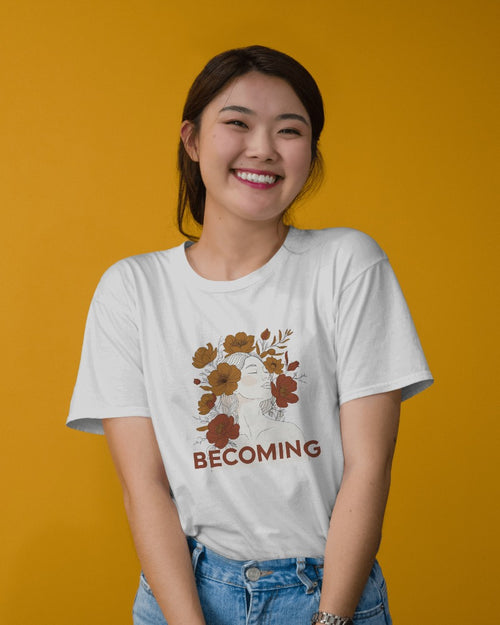 Person wearing a white t-shirt with a floral design and 'BECOMING' text on a yellow background