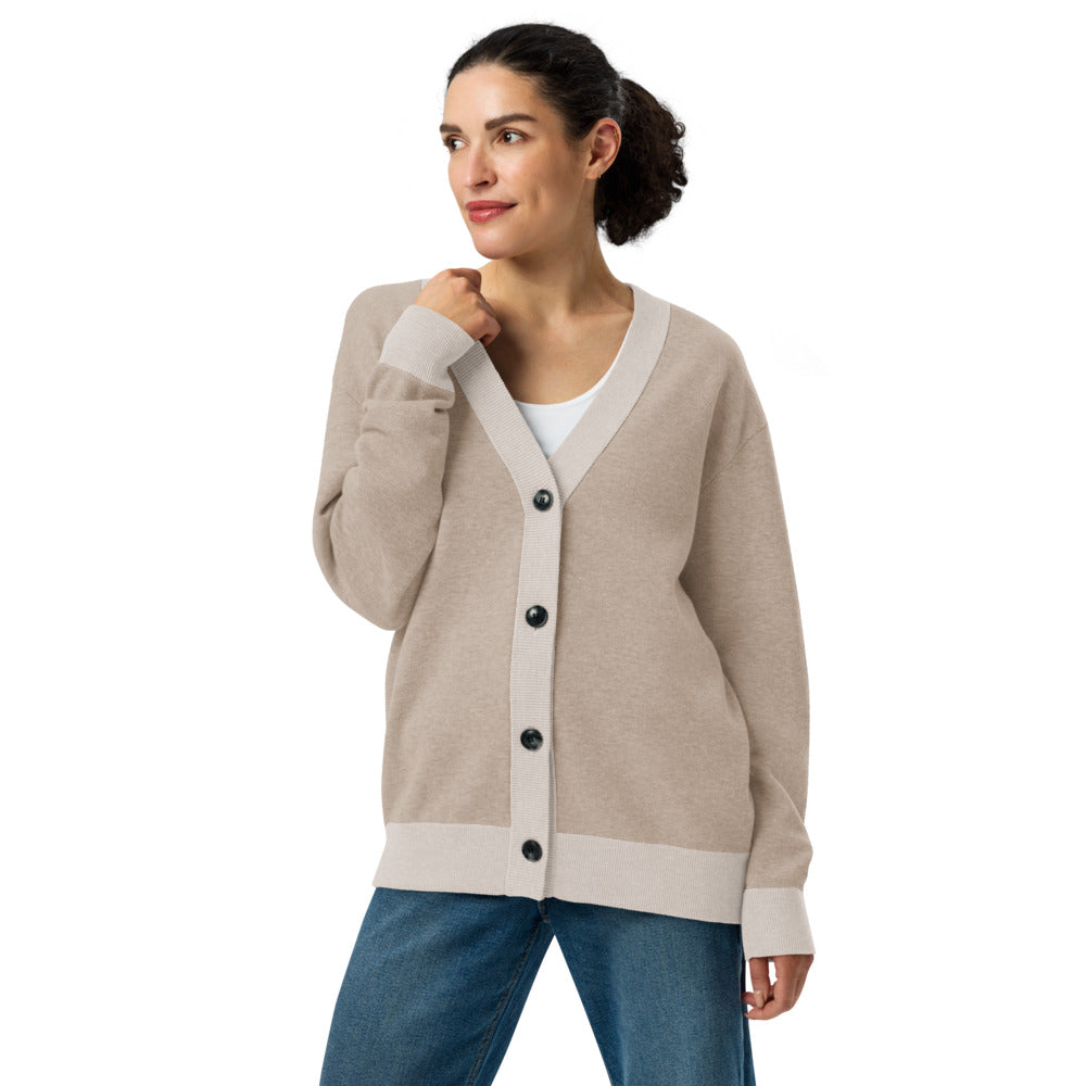 Woman wearing a beige cardigan with black buttons on a white background