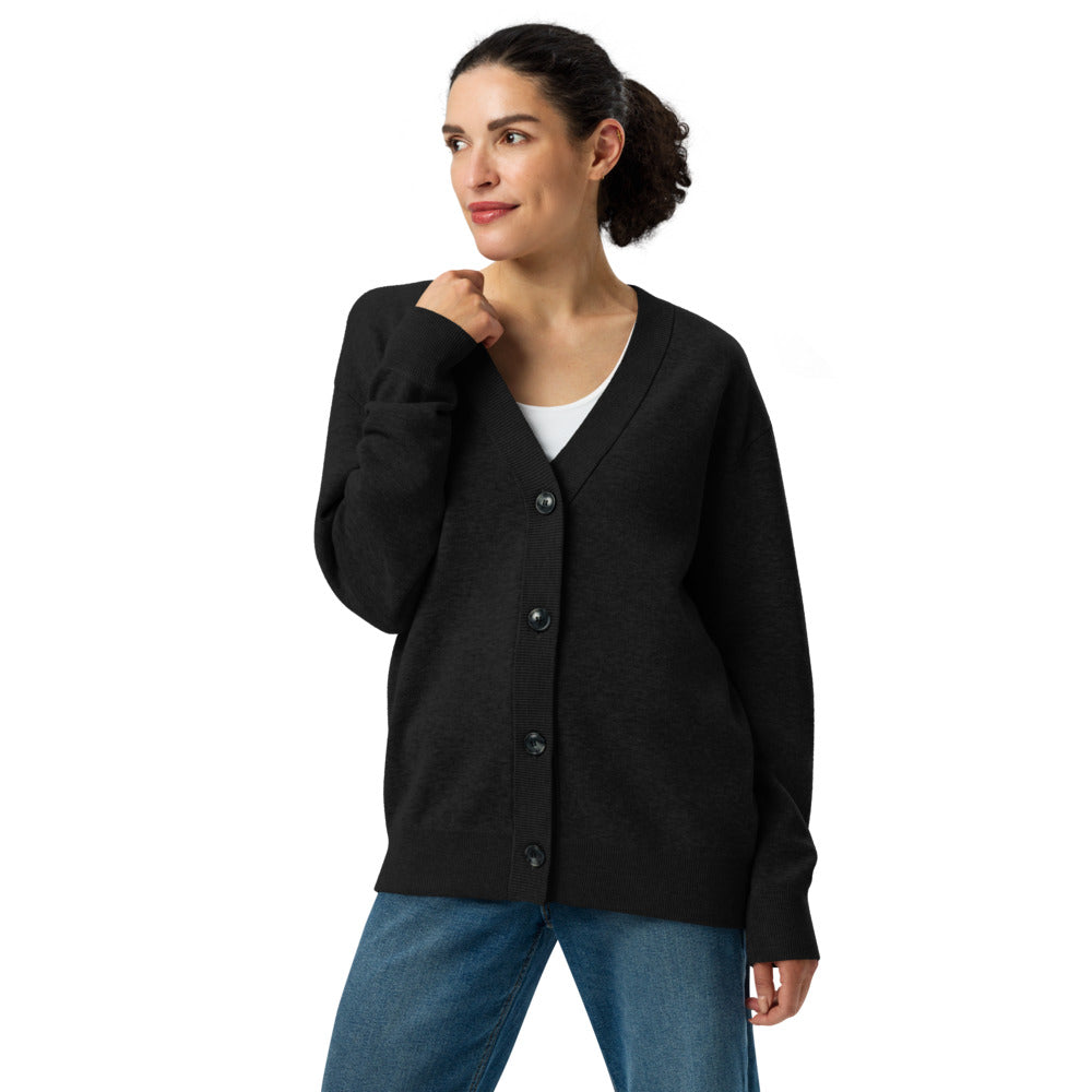 Woman wearing a black cardigan over a white shirt and blue jeans on a white background