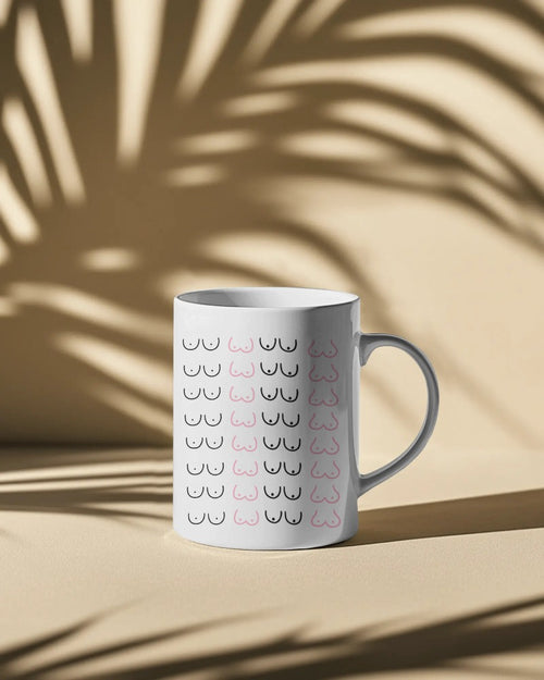 Ceramic mug with minimalist boob print by Savage Cotton, styled on a kitchen counter with coffee and pastel decor