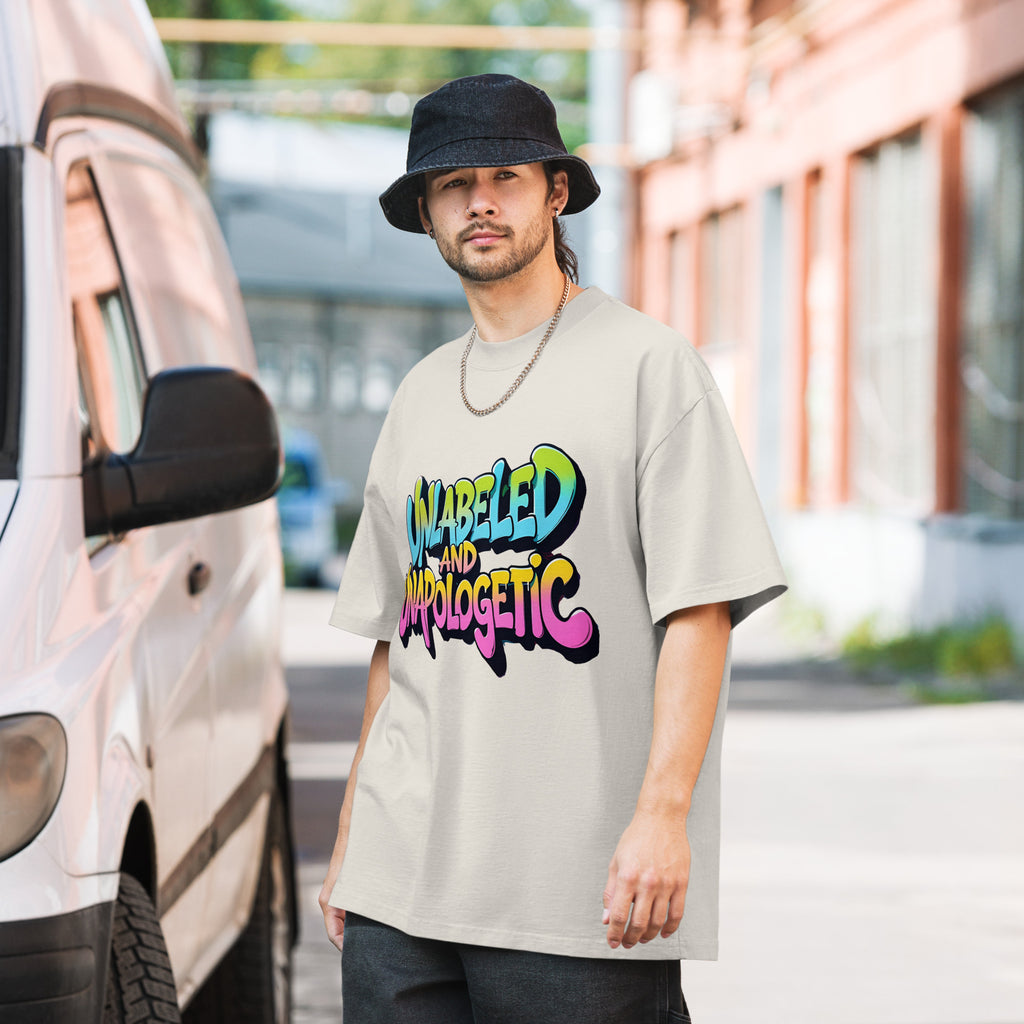 Man wearing a beige t-shirt with colorful text, standing next to a van.