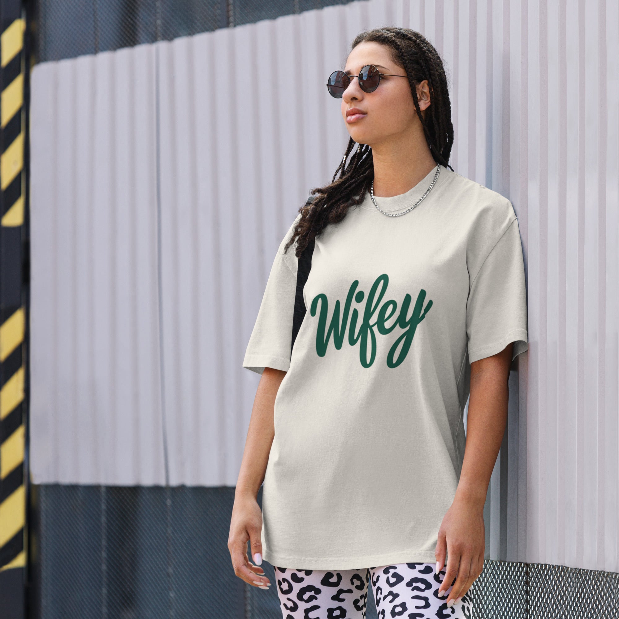 Woman wearing a t-shirt with 'Wifey' text against a striped wall.