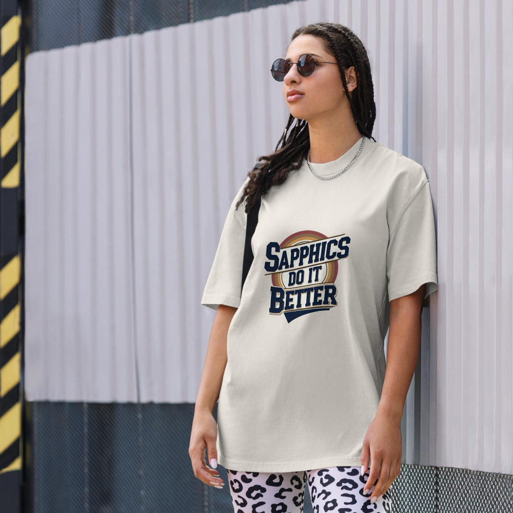 Person wearing a t-shirt with 'Sapphics Do It Better' text against a striped wall.