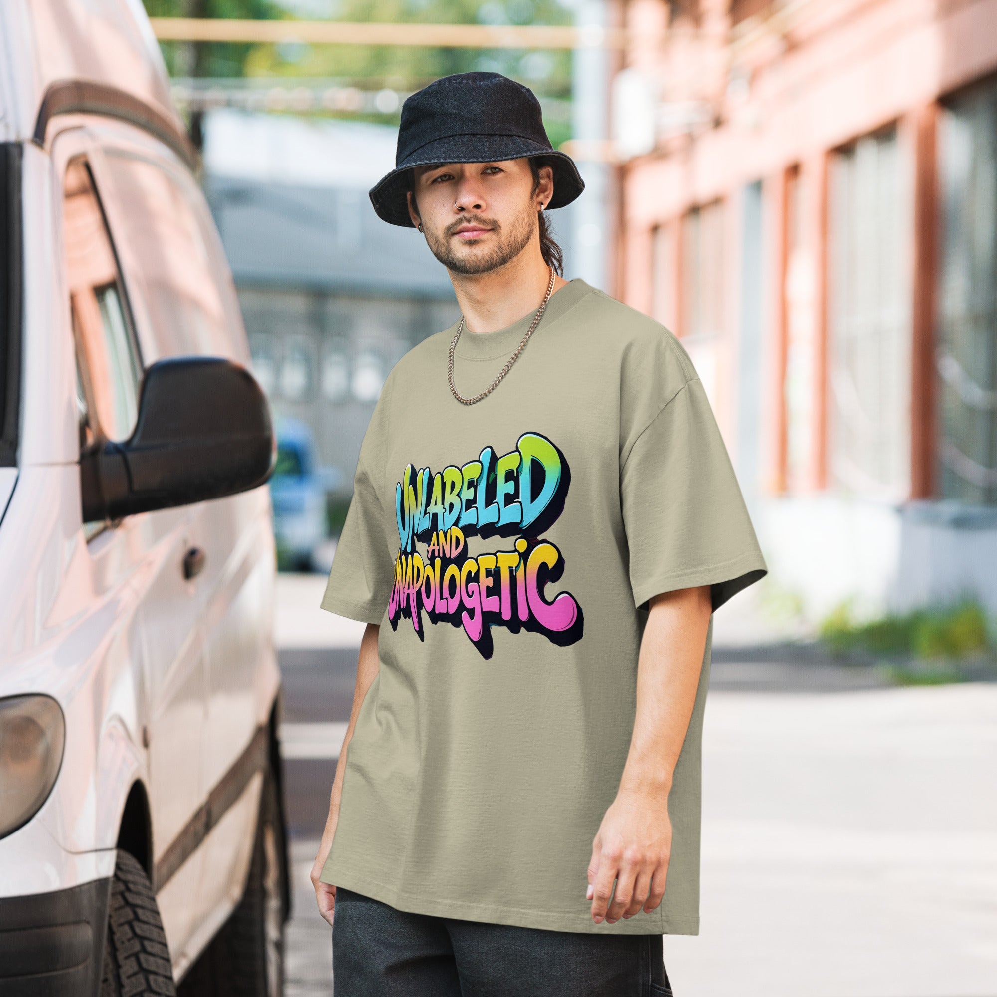 Man wearing a green t-shirt with colorful text standing next to a van.