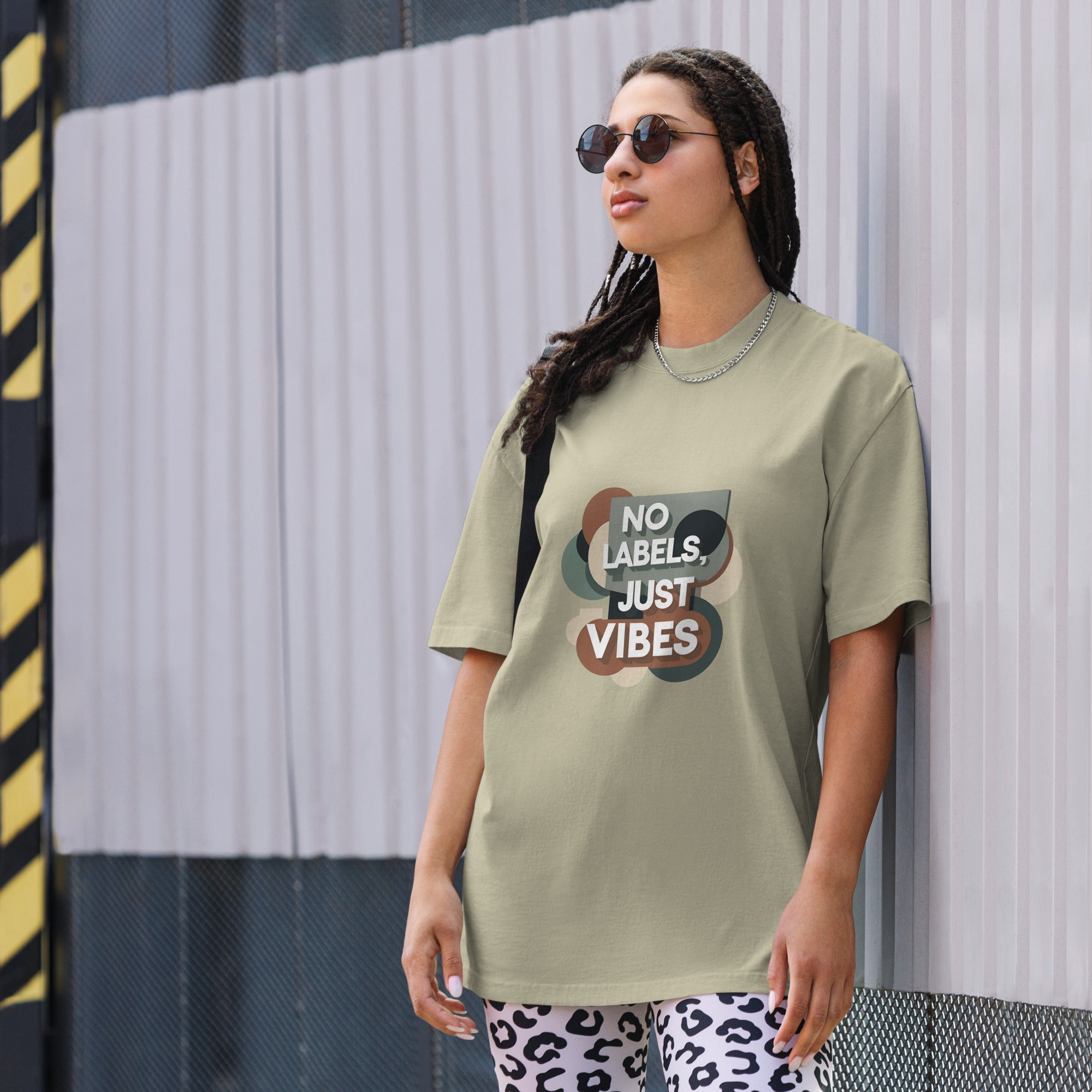 Person wearing a t-shirt with 'No Labels, Just Vibes' text against a striped wall.
