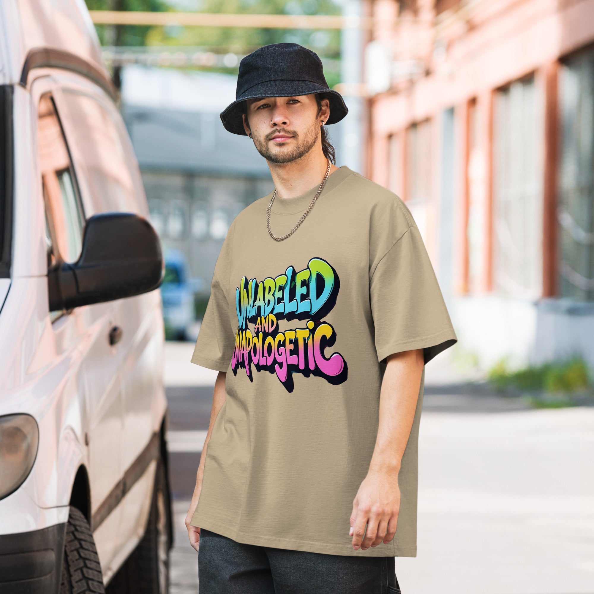 Man wearing a beige t-shirt with colorful text standing next to a vehicle.