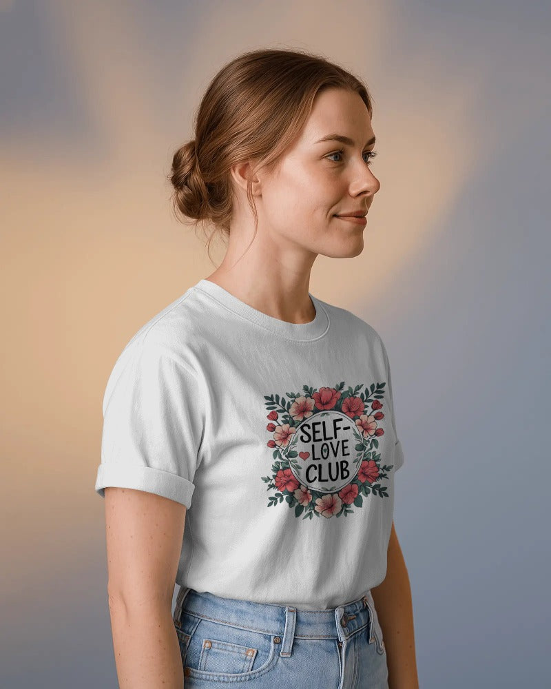 Woman wearing a white t-shirt with 'Self-Love Club' design against a blurred background