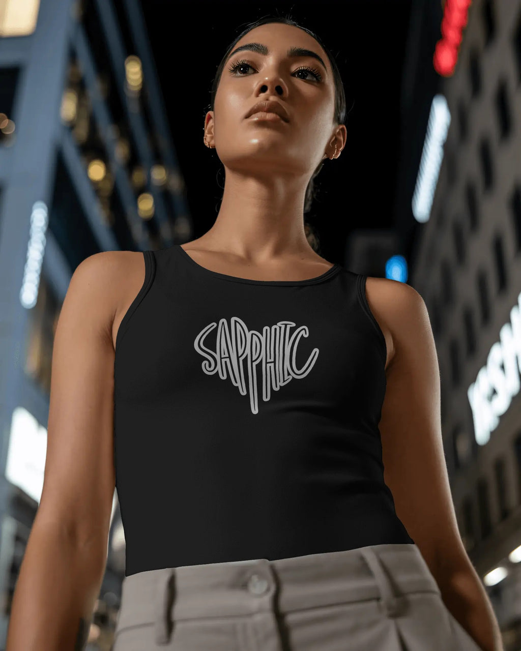 Woman wearing a black tank top with 'Sapphic' text against a cityscape background