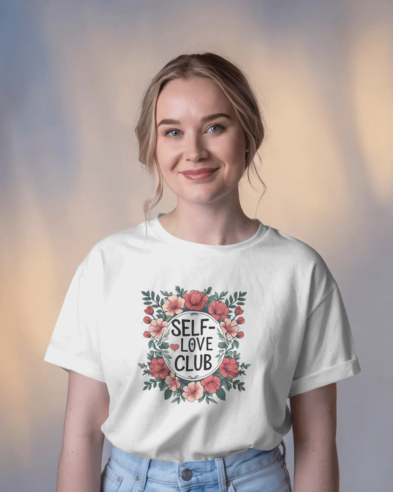 Person wearing a white t-shirt with 'Self Love Club' design on a blurred background