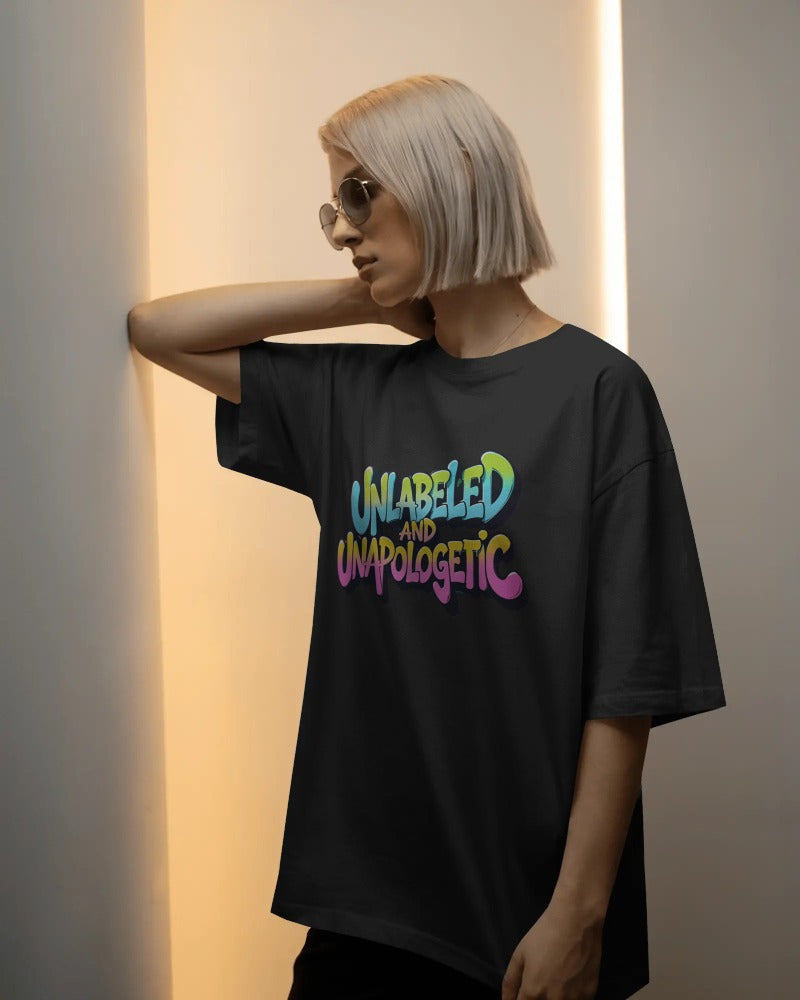 Person wearing a black t-shirt with colorful text 'UNLabeLED AND UNaPOLOGETIC' against a neutral background