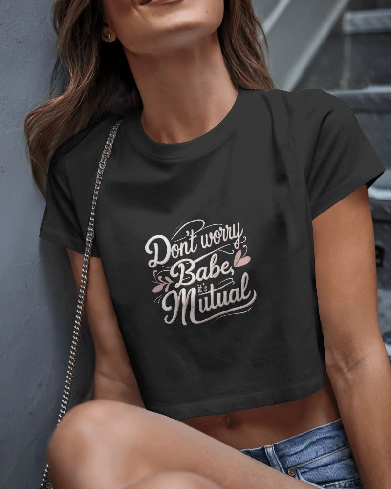 Model wearing Don’t Worry Babe, It’s Mutual cropped slogan T-shirt by Savage Cotton in lilac, styled with shades and a knowing smirk