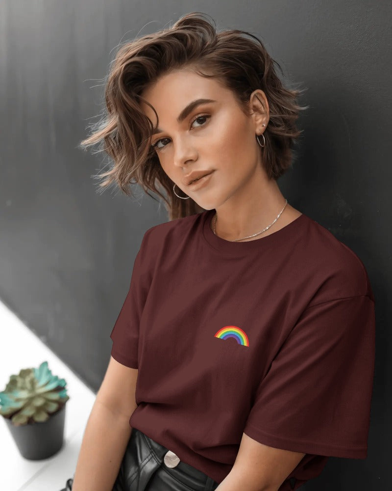 Woman wearing a maroon t-shirt with a rainbow design against a dark background
