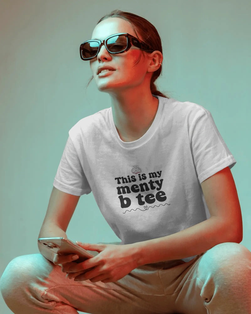 Person wearing a white t-shirt with text sitting against a plain background