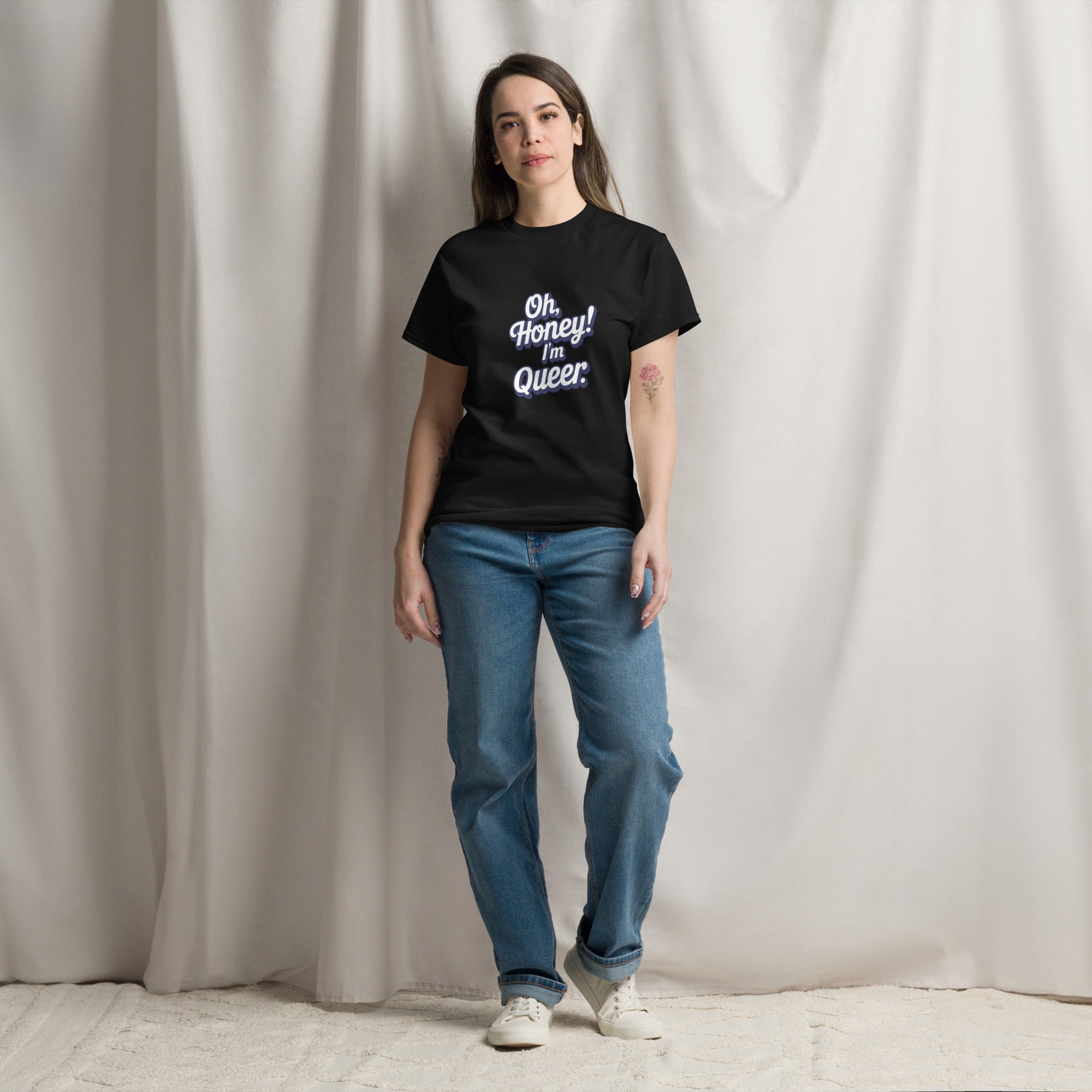 Person wearing a black t-shirt with text and blue jeans standing against a plain background