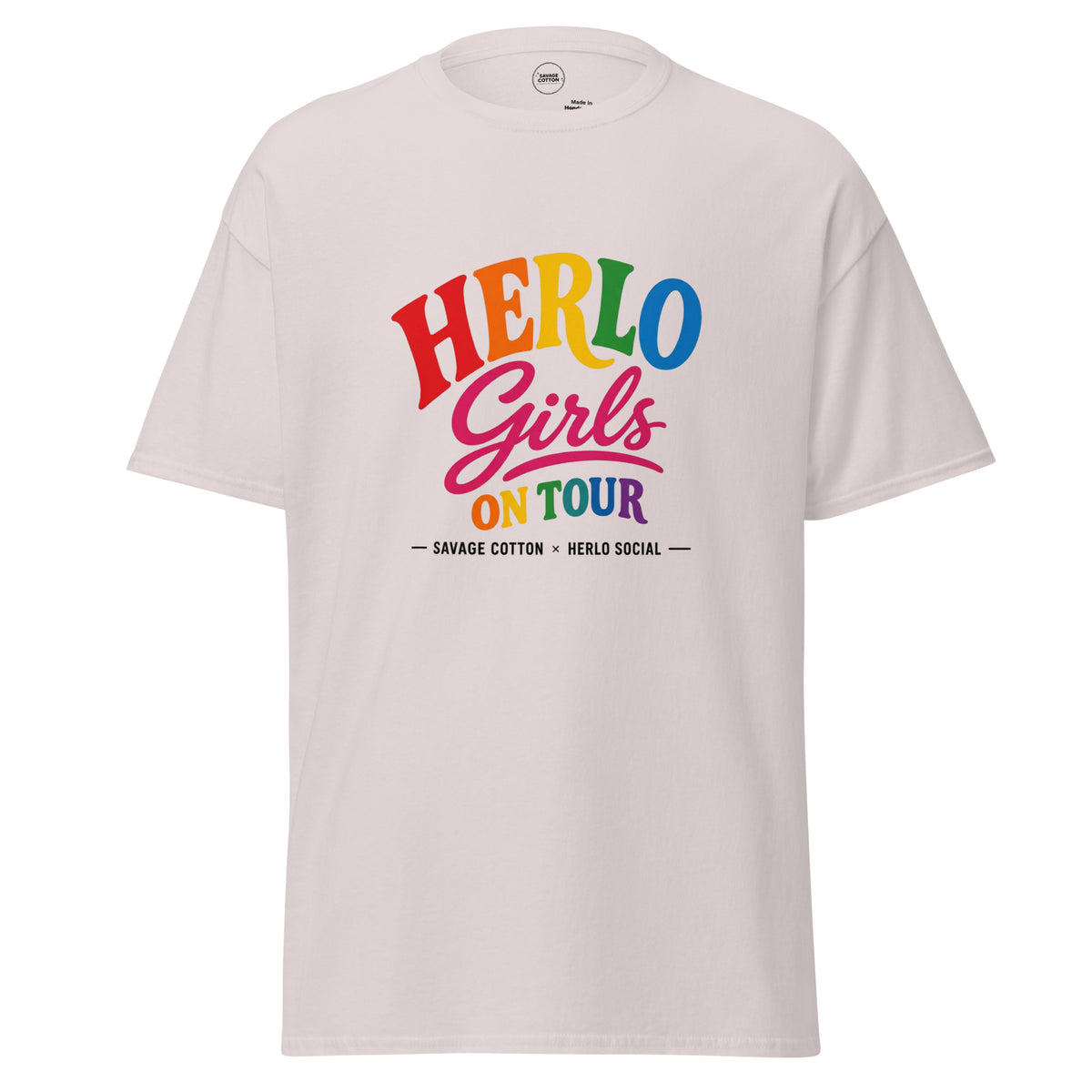 A light beige crewneck t-shirt featuring a colorful graphic on the chest that reads 'HERLO Girls ON TOUR' in rainbow lettering, with 'SAVAGE COTTON' and 'HERLO SOCIAL' printed below.
