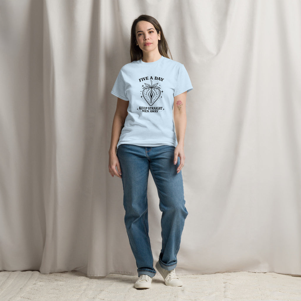 Woman wearing a light blue t-shirt with a graphic design and blue jeans against a plain background