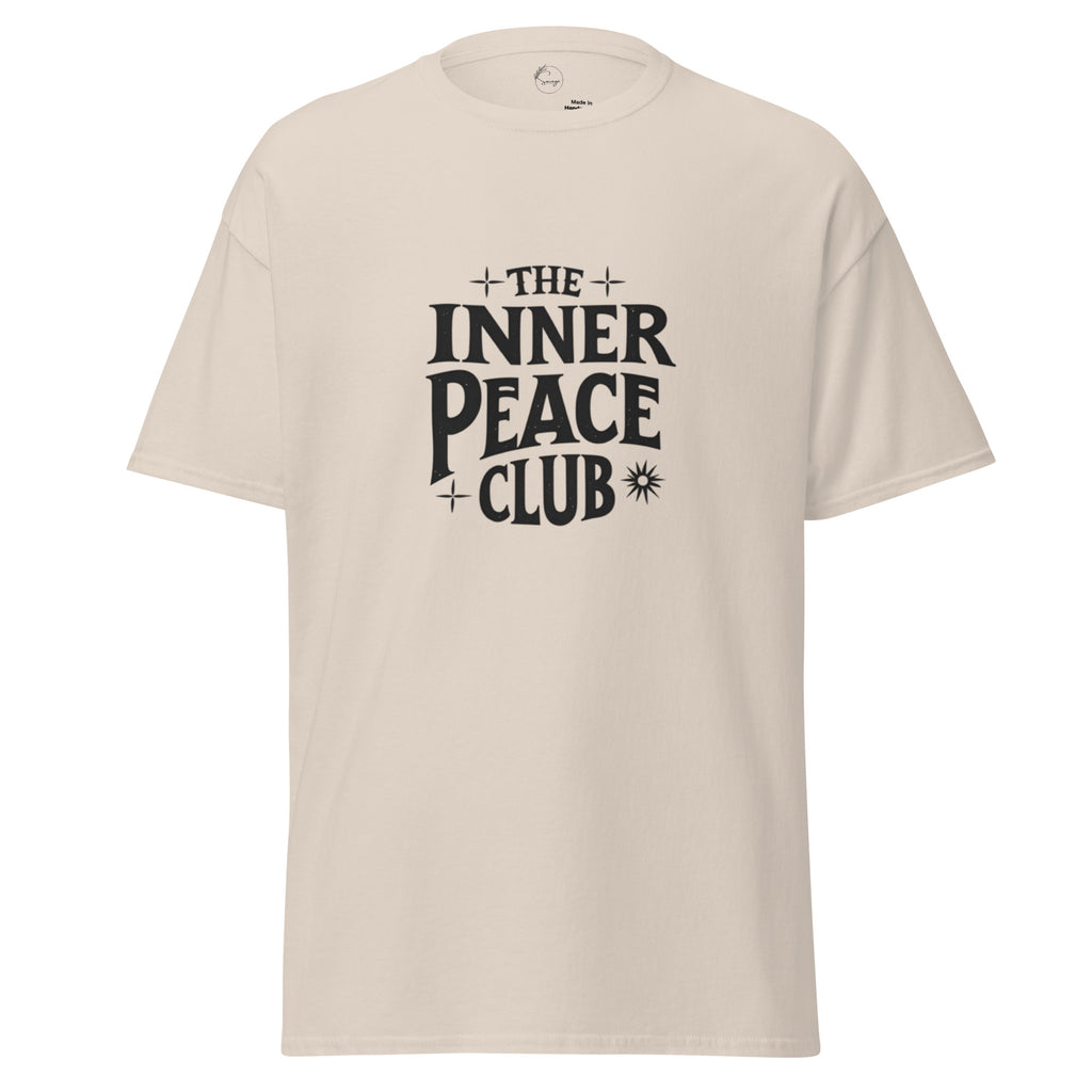 Flat lay of a cream-colored “The Inner Peace Club” t-shirt with soft lettering, styled with pastel accessories and cozy neutral tones.