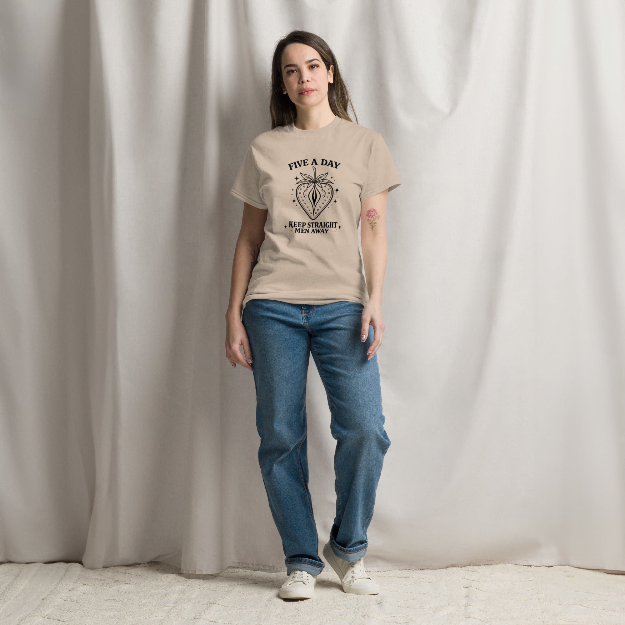 Person wearing a beige t-shirt with 'UPSIDE DOWN' text and blue jeans against a plain background