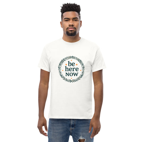 Man wearing a white t-shirt with 'be here NOW' design on a white background