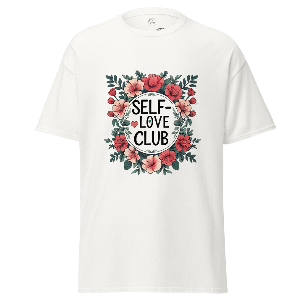 A white short-sleeve crewneck t-shirt featuring a central graphic print with the words 'SELF-LOVE CLUB' in black text inside a white circle, surrounded by a floral wreath of pink flowers and green leaves.