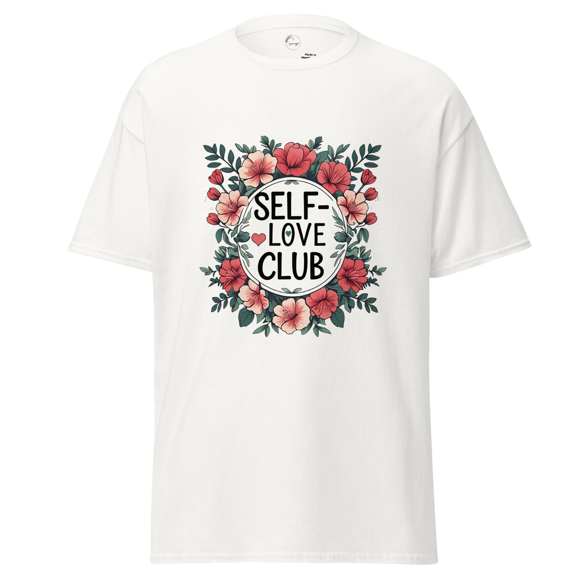 A white short-sleeve crewneck t-shirt featuring a central graphic print with the words 'SELF-LOVE CLUB' in black text inside a white circle, surrounded by a floral wreath of pink flowers and green leaves.