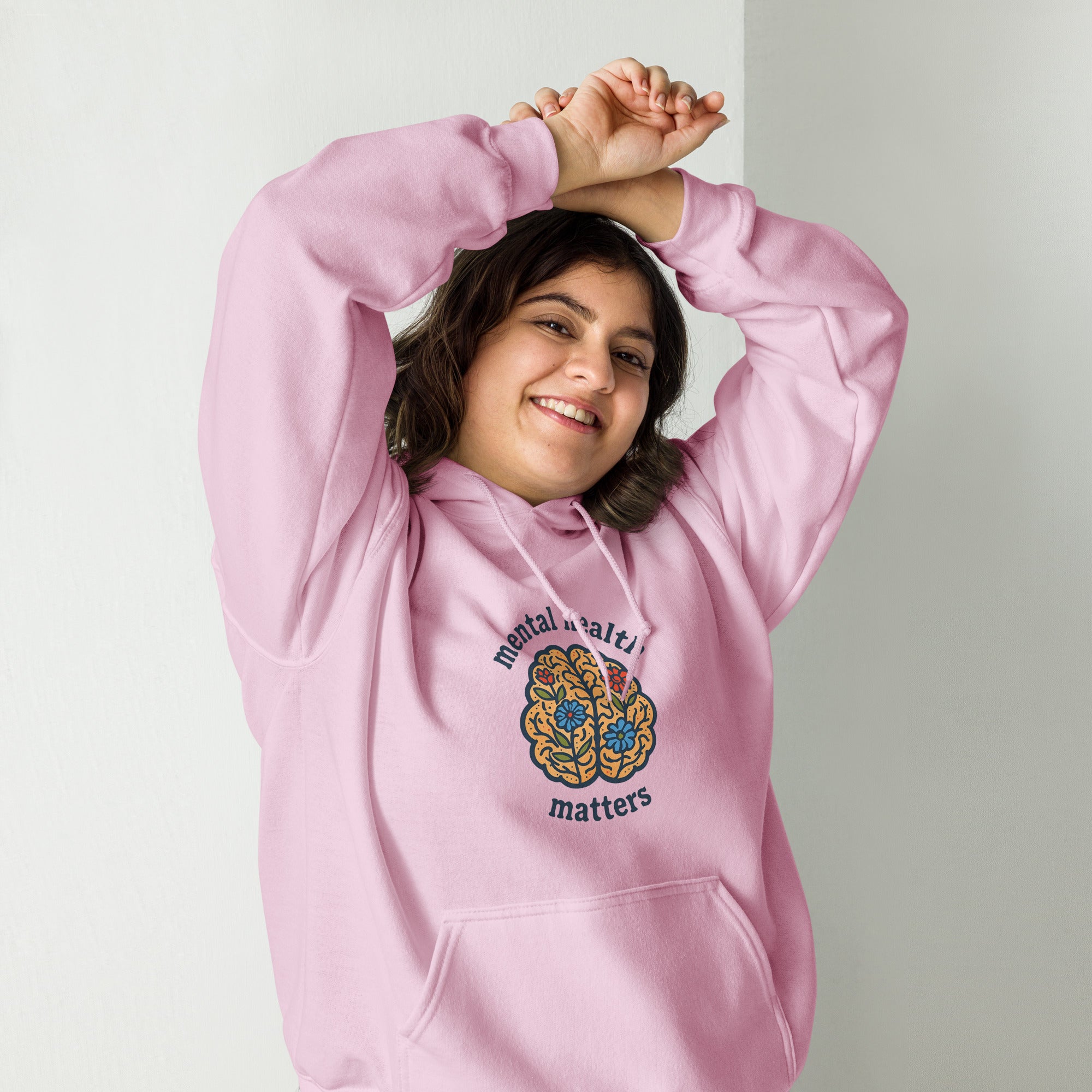 Person wearing a pink hoodie with a colorful design and text on a plain background