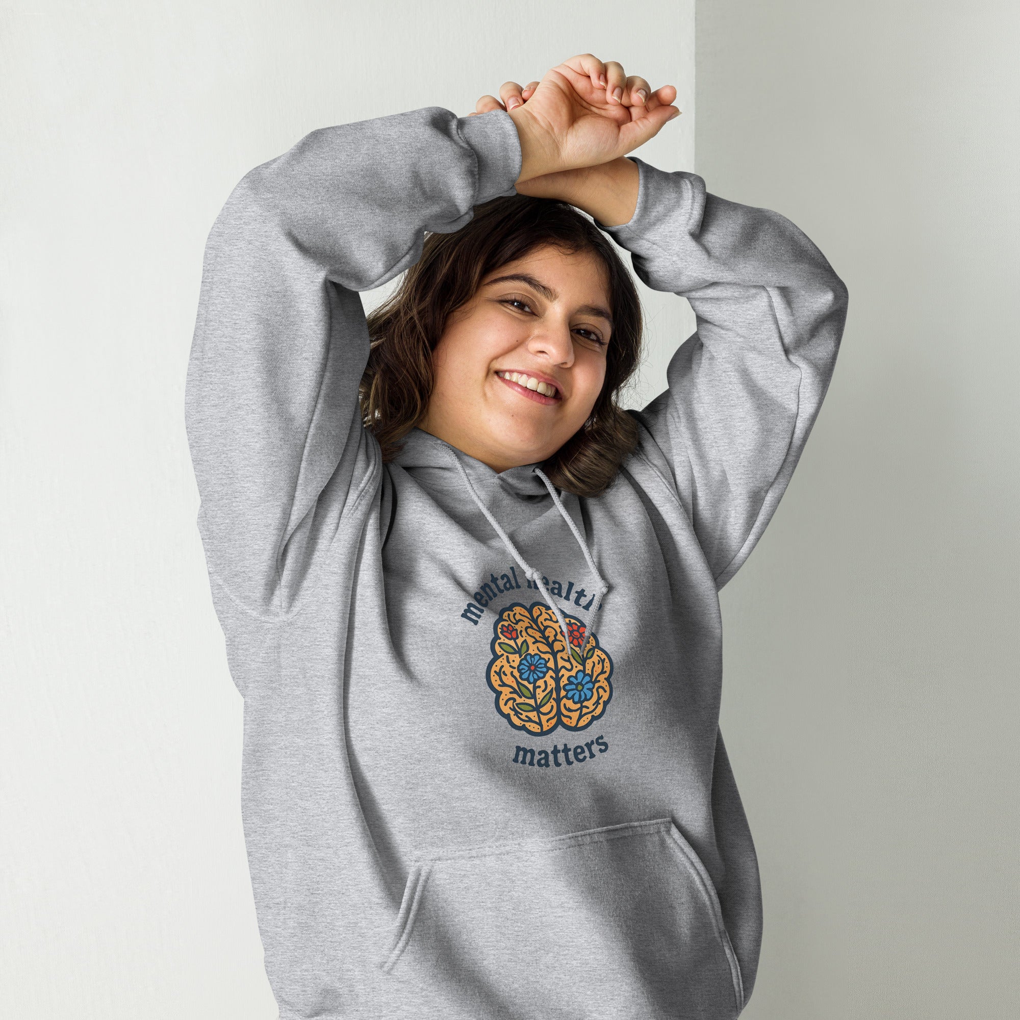 Person wearing a gray hoodie with a logo and text on a plain background