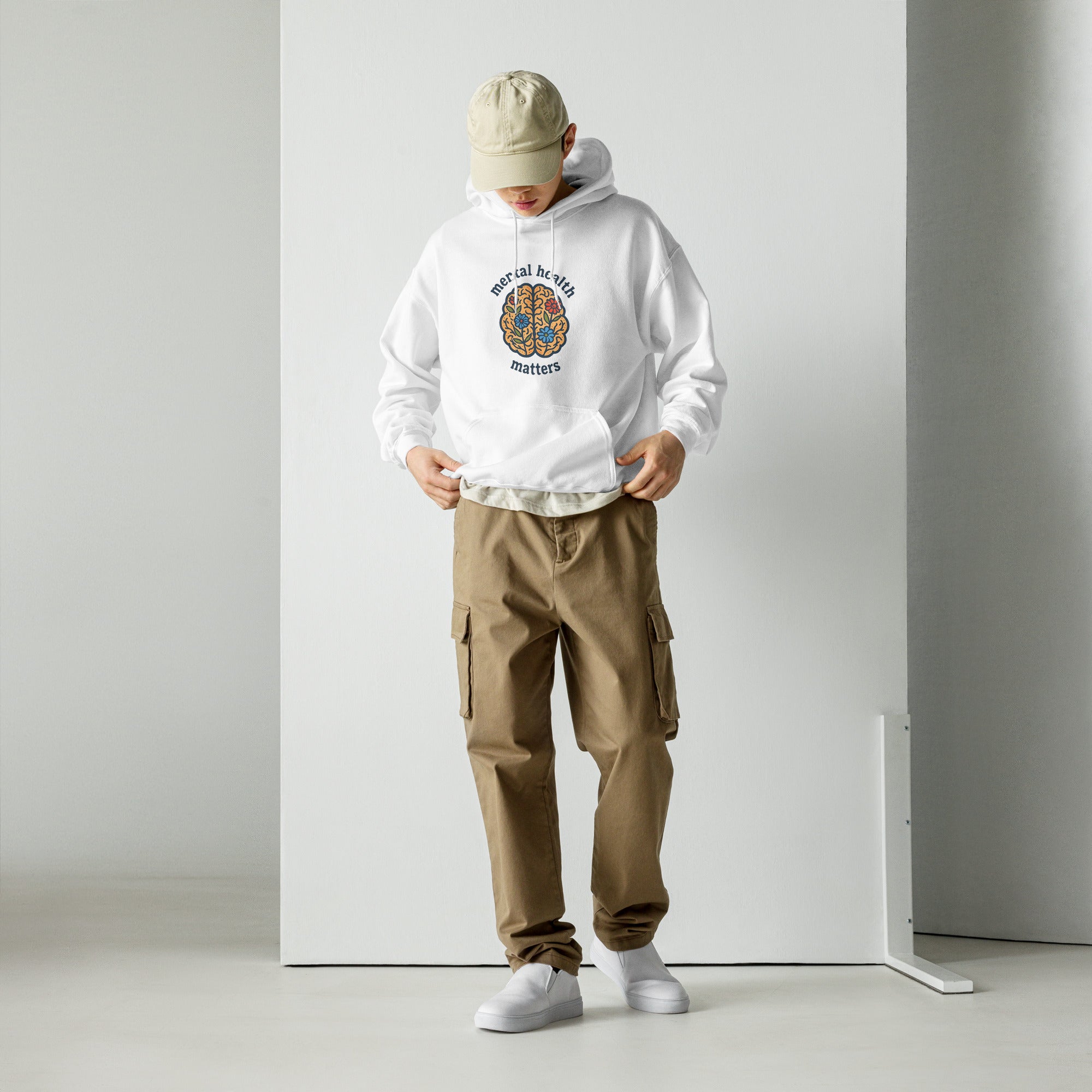 Person wearing a white hoodie with a logo and brown cargo pants against a plain background