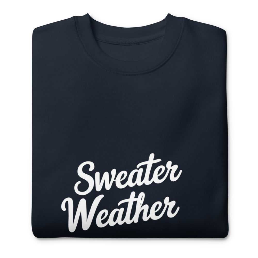 Folded navy blue sweatshirt with 'Sweater Weather' text on a white background