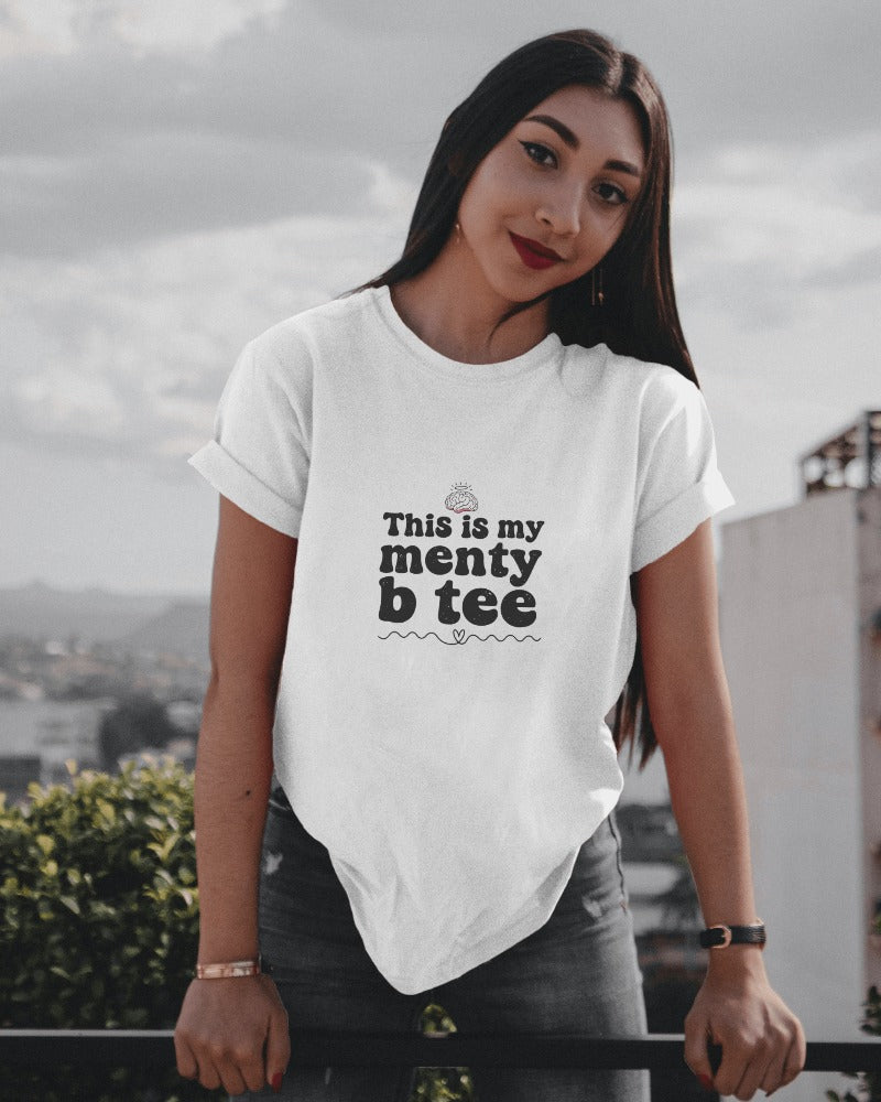 Woman wearing a white t-shirt with text on it, standing outdoors.