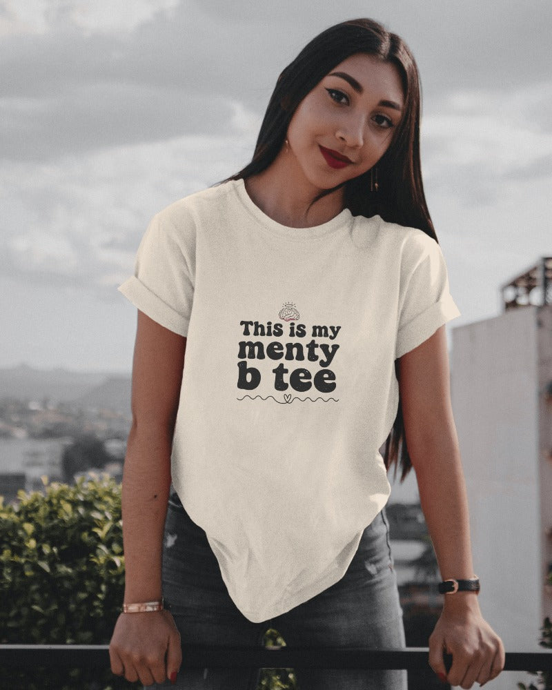 Woman wearing a white t-shirt with text on it, standing outdoors.