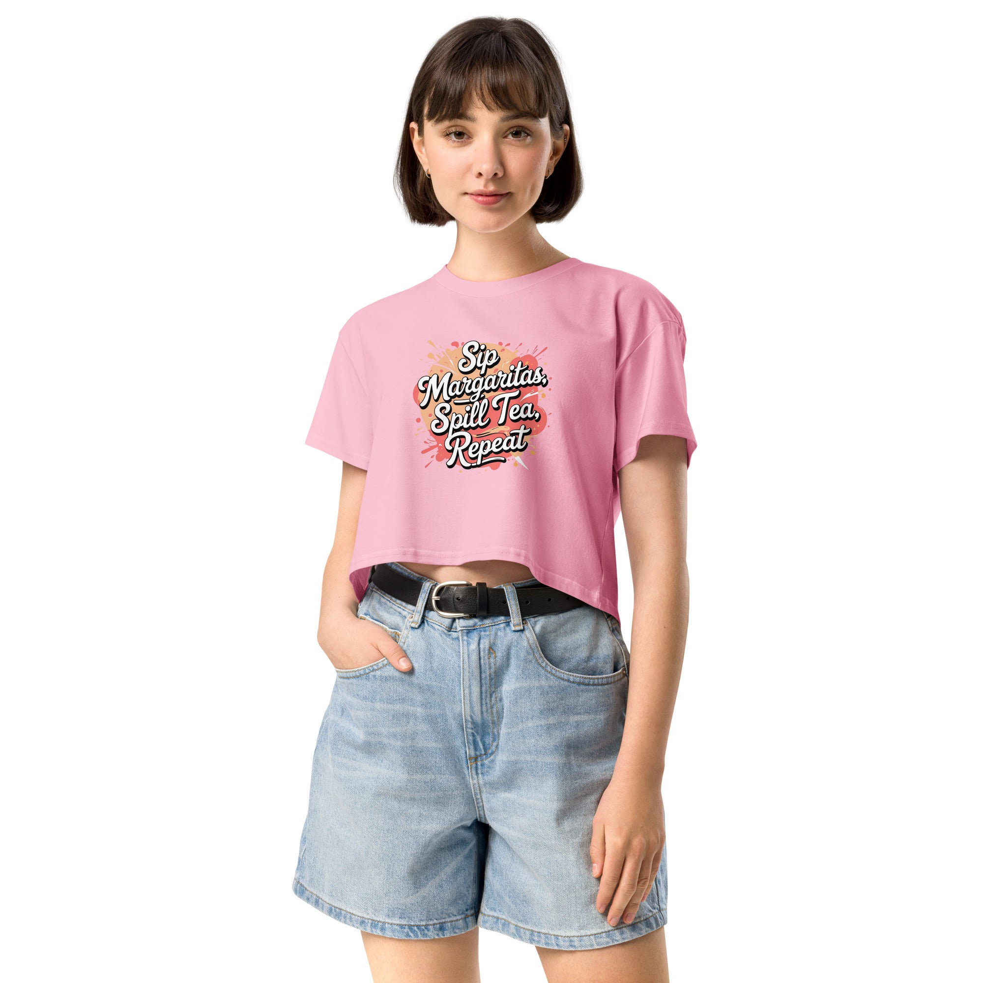 Model wearing Sip Margaritas, Spill Tea, Repeat cropped slogan T-shirt by Savage Cotton in pastel pink, styled with sunglasses and cocktail in hand