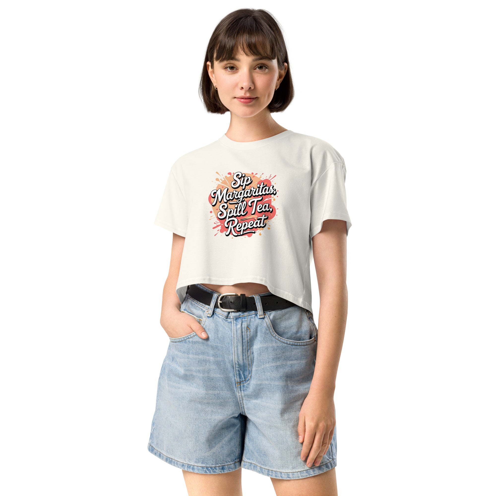 Model wearing Sip Margaritas, Spill Tea, Repeat cropped slogan T-shirt by Savage Cotton in pastel pink, styled with sunglasses and cocktail in hand