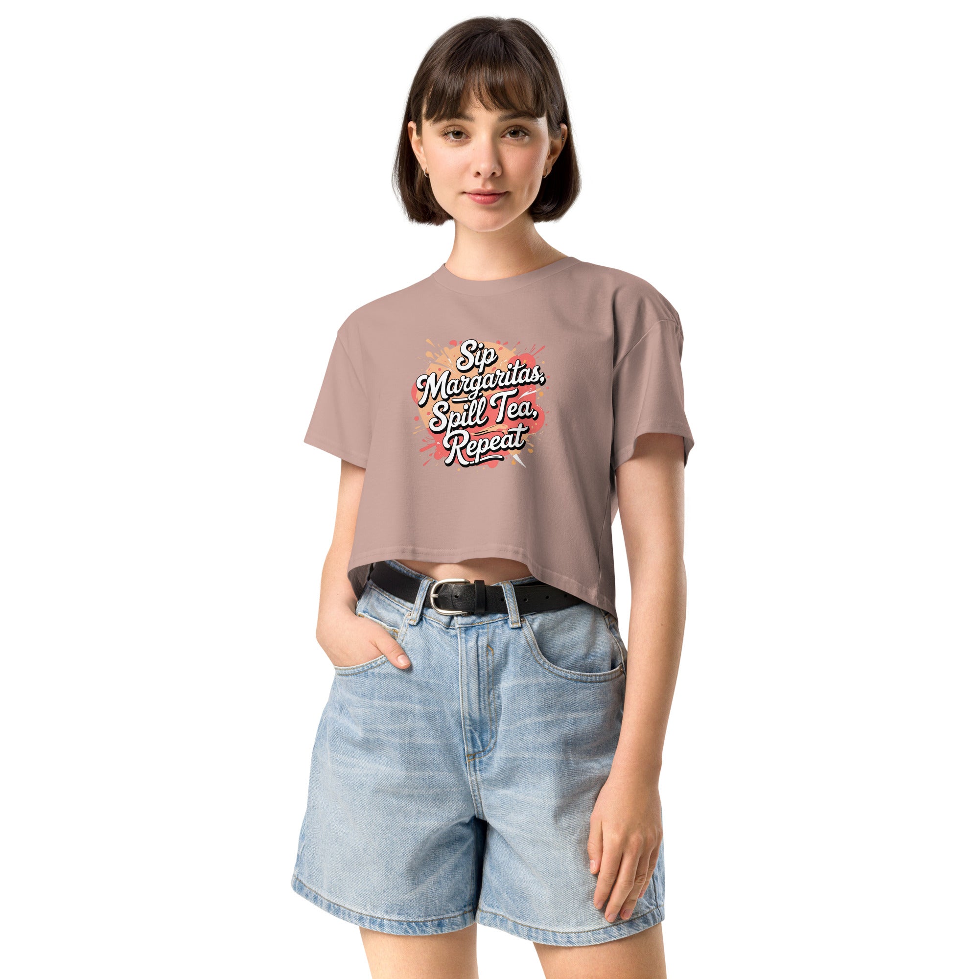 Model wearing Sip Margaritas, Spill Tea, Repeat cropped slogan T-shirt by Savage Cotton in pastel pink, styled with sunglasses and cocktail in hand